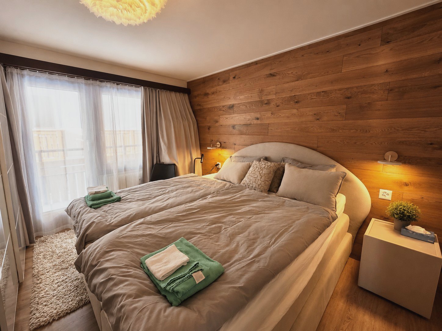 Deuxième chambre d'Auri avec deux lits, paroi en bois et vue sur le balcon