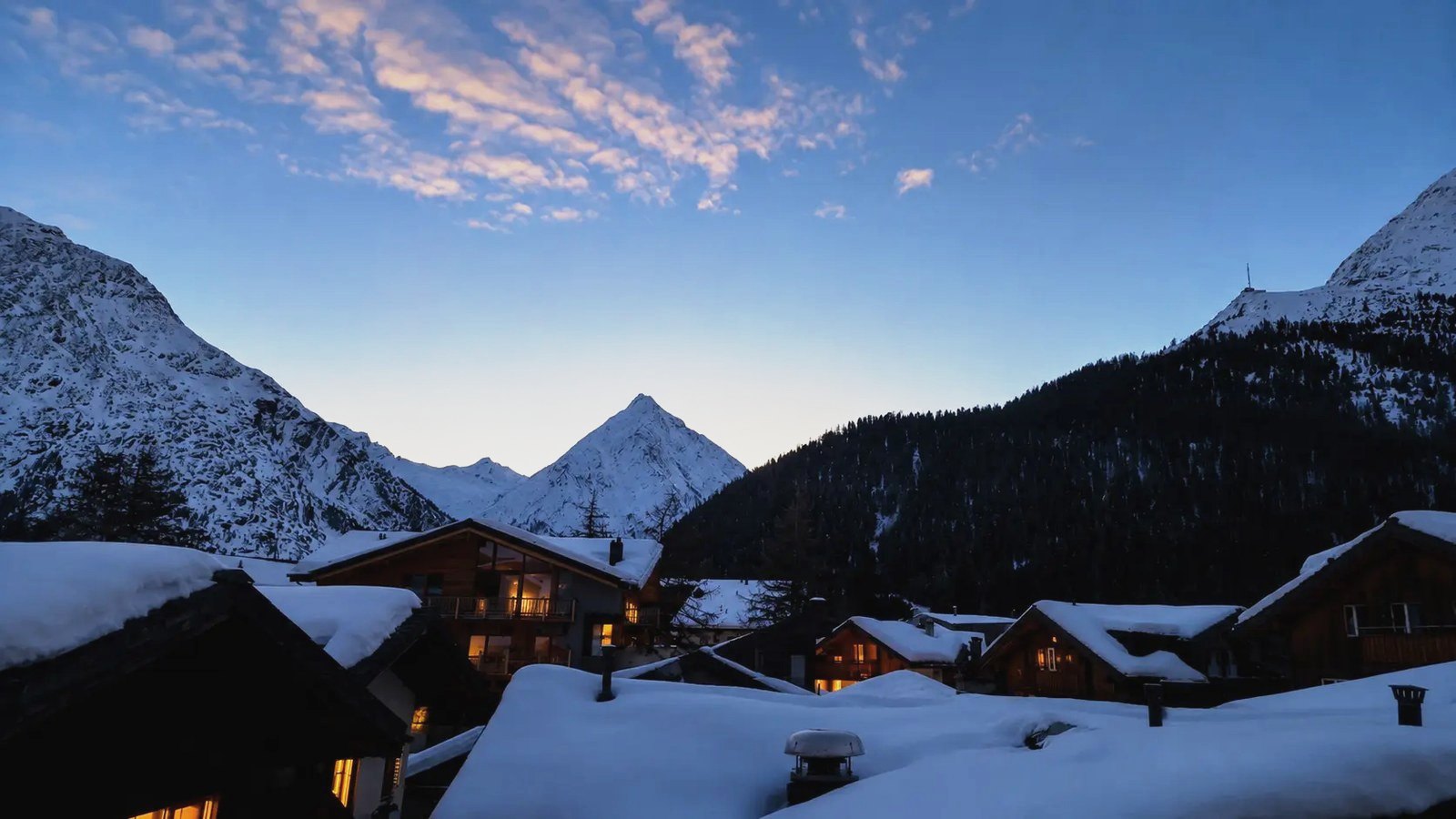 Evening over Saas-Fee: snowy rooftops and glowing windows below the 4,000-metre peaks of Valais