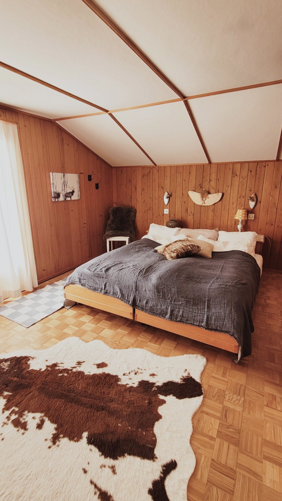 Gemütliches Schlafzimmer im Chalet Nördli mit Holzwänden, Doppelbett, Fell und Kuhfellteppich