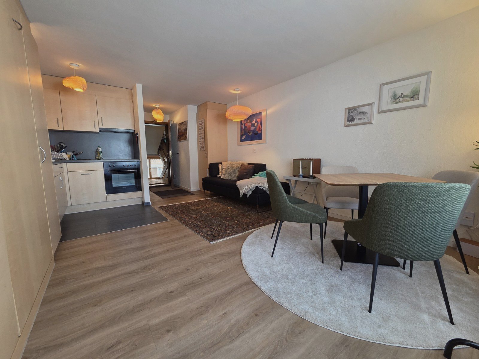 Open-plan kitchen of the Malo studio in Saas-Fee with light wood, bench seating and dining area