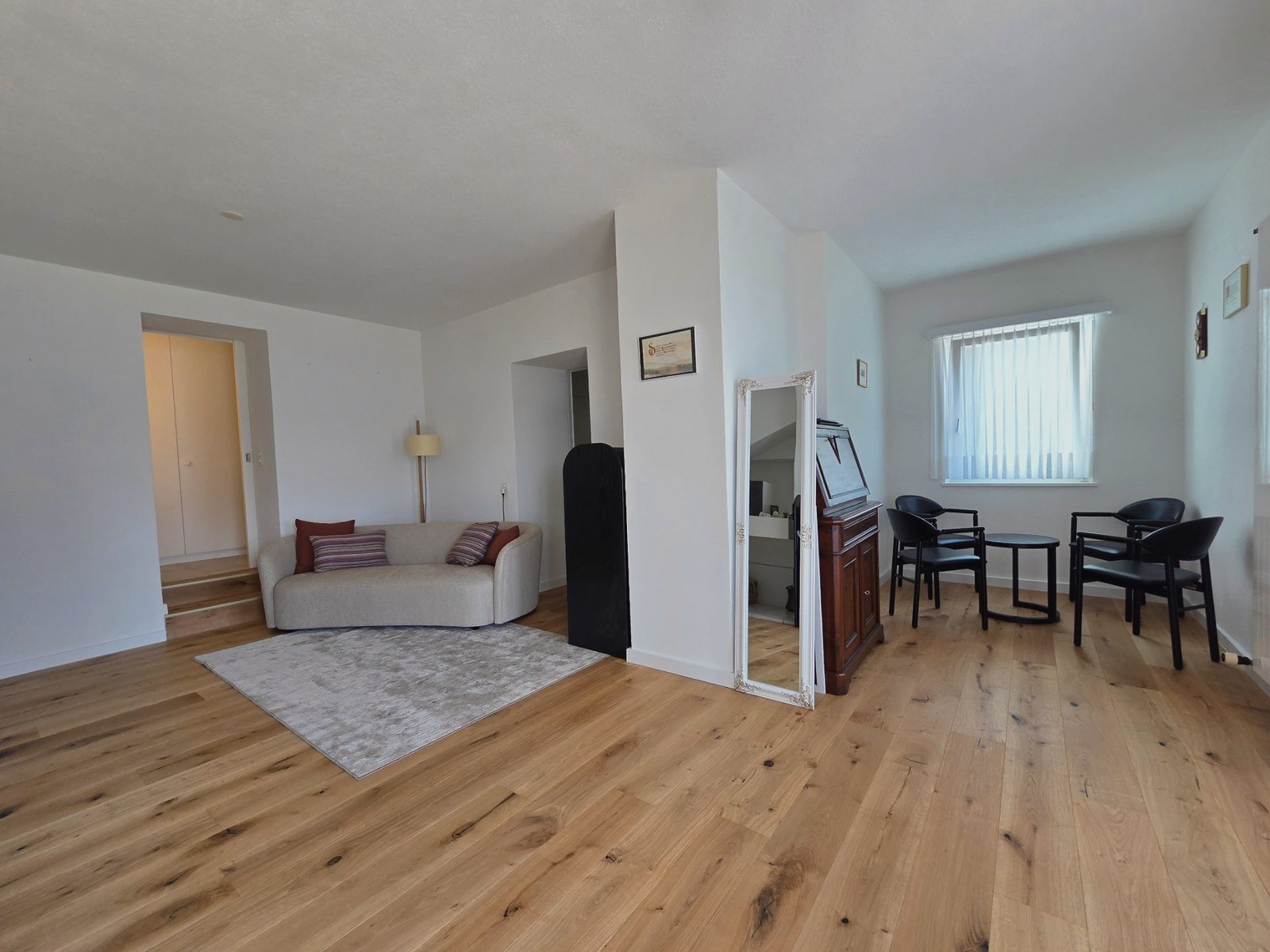 Weitläufiger Wohnraum von Soleo mit Sofa, Vintage-Schrank, Spiegel und Sitzecke